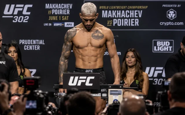Lutador sem camisa na balança durante a pesagem oficial do UFC 302, cercado por fotógrafos