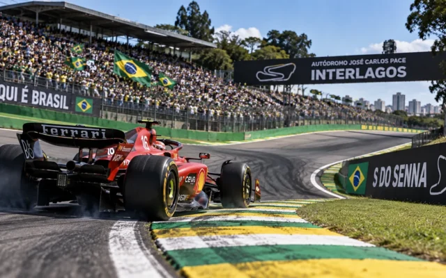 Carro de Fórmula 1 vermelho contorna a curva do S do Senna em Interlagos, com a torcida ao fundo